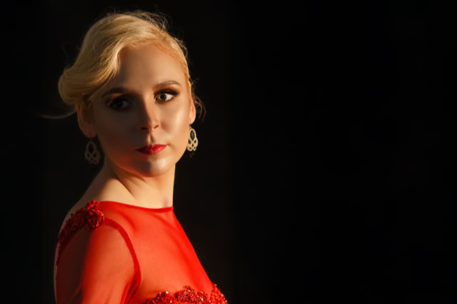 Blondynka w czerwonej wieczorowej sukni, spogląda wstecz. Portretowa Sesja Fotograficzna. Kobieca sesja zdjęciowa. Portret Kobiety.